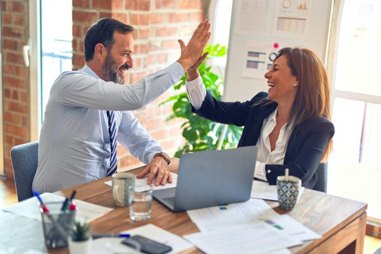 Fünf Personen stehen zusammen und legen ihre Hände in der Mitte übereinander.