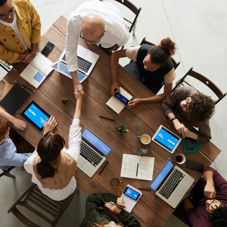 Menschen in einem Meetingraum, die an einem Tisch mit Laptops und Notizen arbeiten.