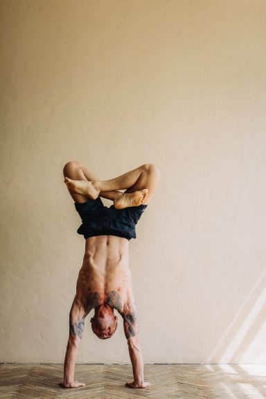 Ein Mann macht einen Handstand in einem hellen Raum mit minimalem Dekor.